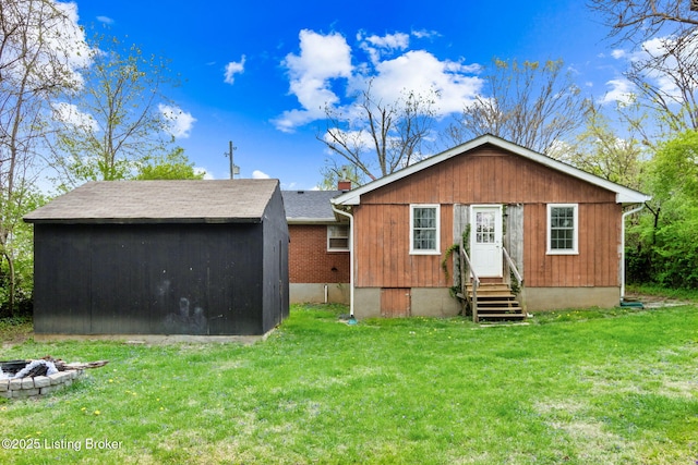 back of property with a chimney, entry steps, a yard, an outdoor structure, and an outdoor fire pit