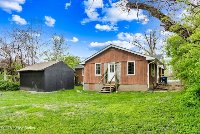 rear view of house featuring a lawn, an outdoor structure, entry steps, and a shed