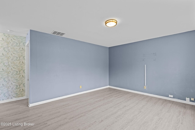 spare room featuring baseboards, wood finished floors, and visible vents