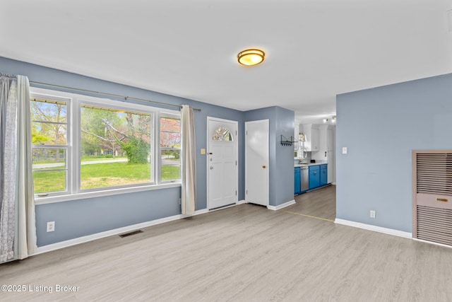 foyer entrance featuring visible vents, baseboards, heating unit, and wood finished floors