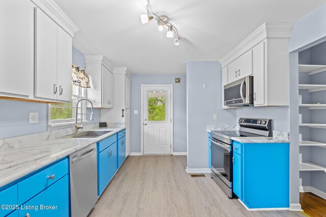 kitchen with light wood-style flooring, appliances with stainless steel finishes, blue cabinets, and a sink