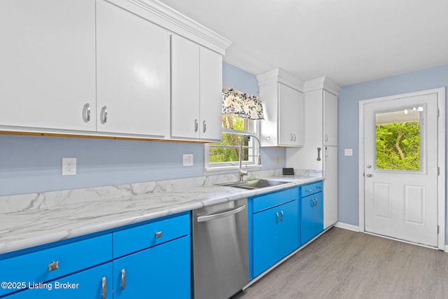 kitchen featuring blue cabinets, stainless steel dishwasher, a sink, light wood-style floors, and white cabinetry
