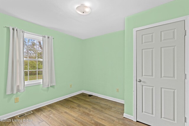 unfurnished bedroom featuring wood finished floors, visible vents, and baseboards