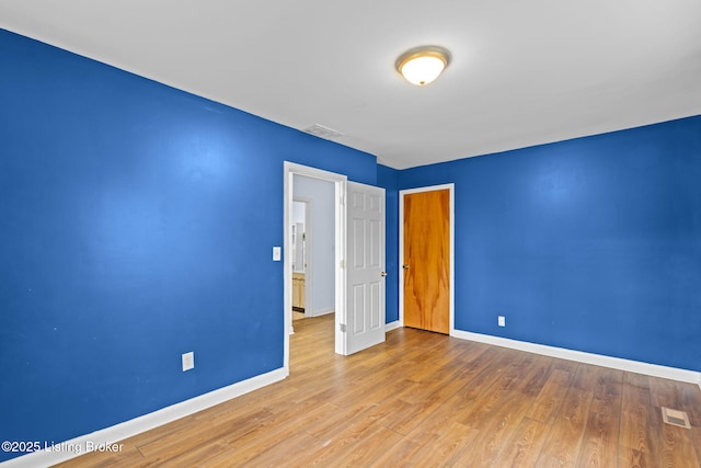 spare room featuring baseboards, wood finished floors, and visible vents