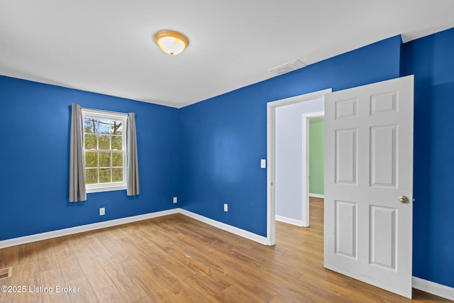 unfurnished bedroom featuring wood finished floors, visible vents, and baseboards