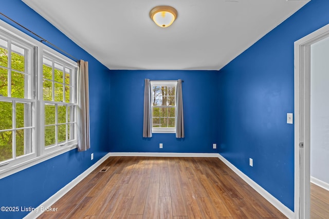 spare room with visible vents, baseboards, and wood-type flooring