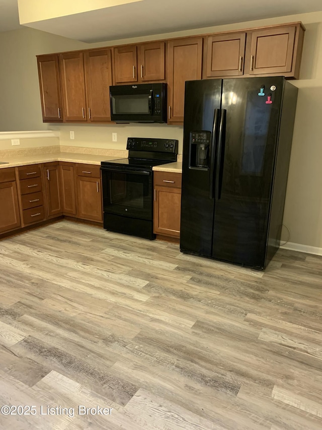 1015 E Muhammad Ali Blvd, Louisville, KY 40204 - kitchen with black appliances, light wood-style floors, brown cabinetry, and light countertops