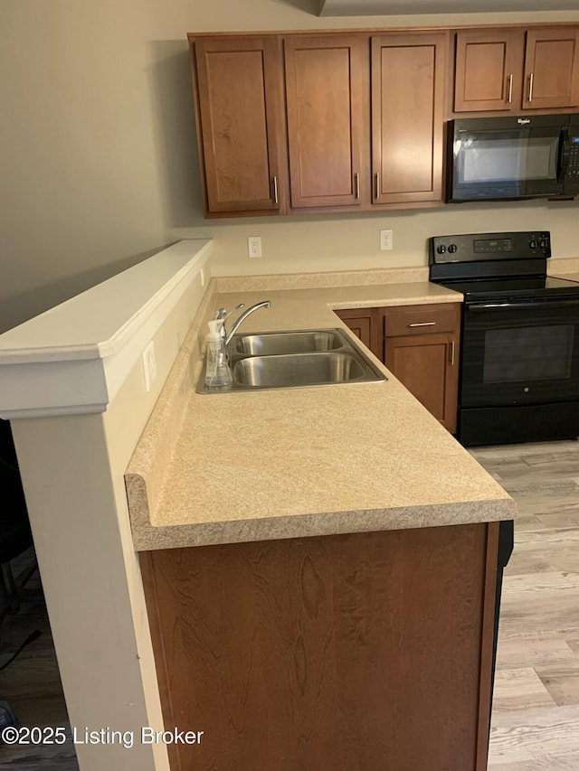 1015 E Muhammad Ali Blvd, Louisville, KY 40204 - kitchen featuring black appliances, light wood-type flooring, light countertops, a peninsula, and brown cabinetry