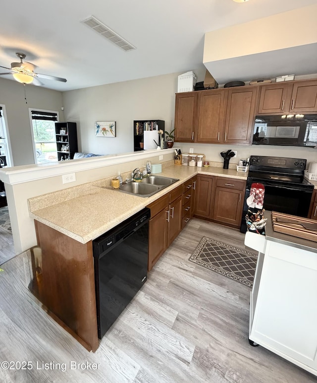1015 E Muhammad Ali Blvd, Louisville, KY 40204 - kitchen with black appliances, a peninsula, light wood-style floors, a ceiling fan, and light countertops