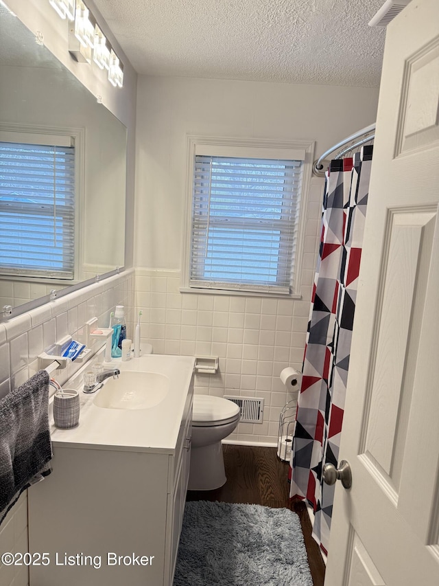 full bath featuring tile walls, visible vents, toilet, and vanity