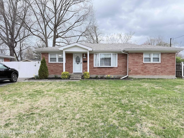 single story home featuring brick siding, a shingled roof, a front lawn, and fence
