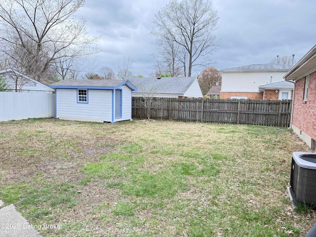 view of yard with a fenced backyard, an outdoor structure, cooling unit, and a storage unit