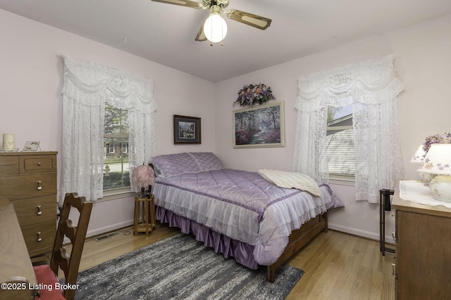 bedroom featuring visible vents, baseboards, wood finished floors, and ceiling fan