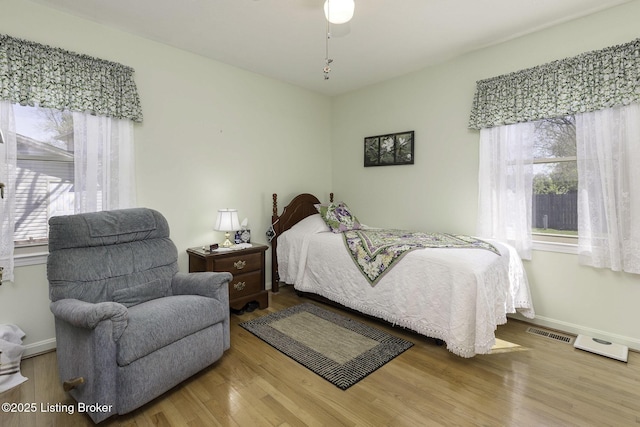 bedroom with wood finished floors, visible vents, and baseboards