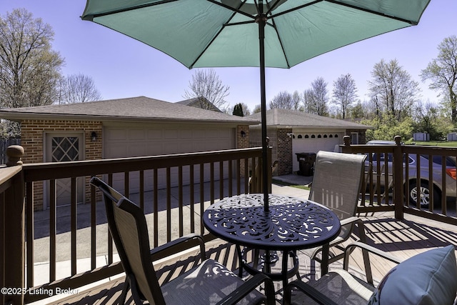 wooden deck with a garage, outdoor dining space, and an outbuilding