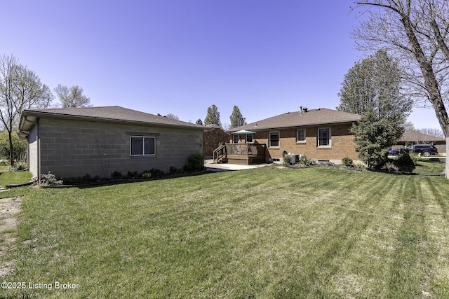 back of house with a yard, concrete block siding, and a deck