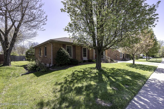 ranch-style home featuring brick siding, fence, and a front yard