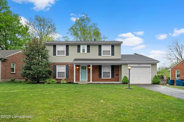 traditional home featuring a garage, brick siding, a front yard, and aphalt driveway