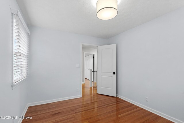 spare room with baseboards and wood finished floors