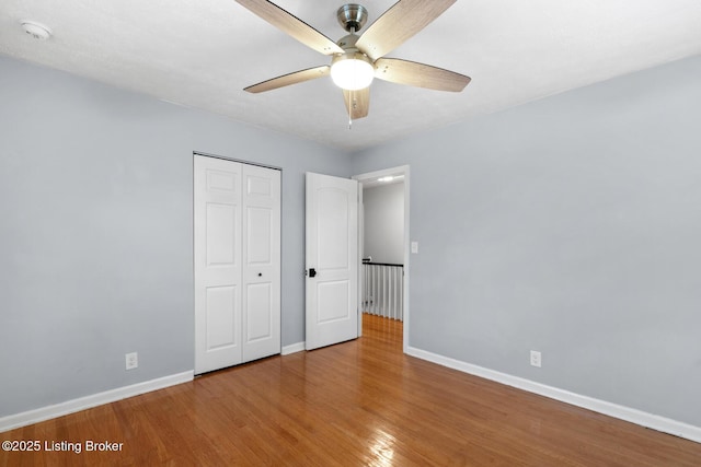 unfurnished bedroom with ceiling fan, baseboards, wood finished floors, and a closet
