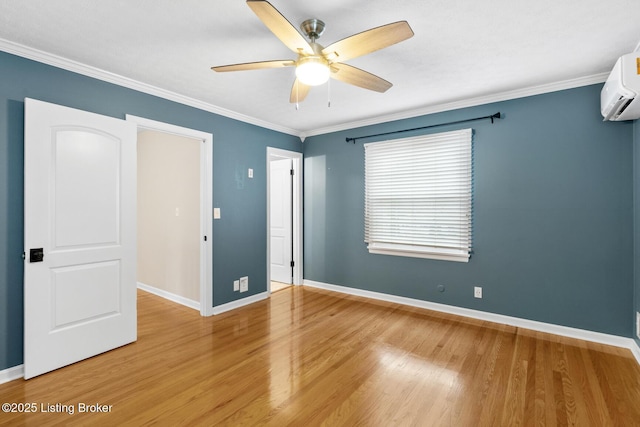unfurnished bedroom featuring light wood-style flooring, baseboards, a wall unit AC, and crown molding