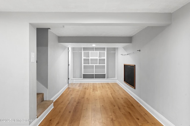 bonus room featuring stairway, baseboards, beam ceiling, and light wood-style floors