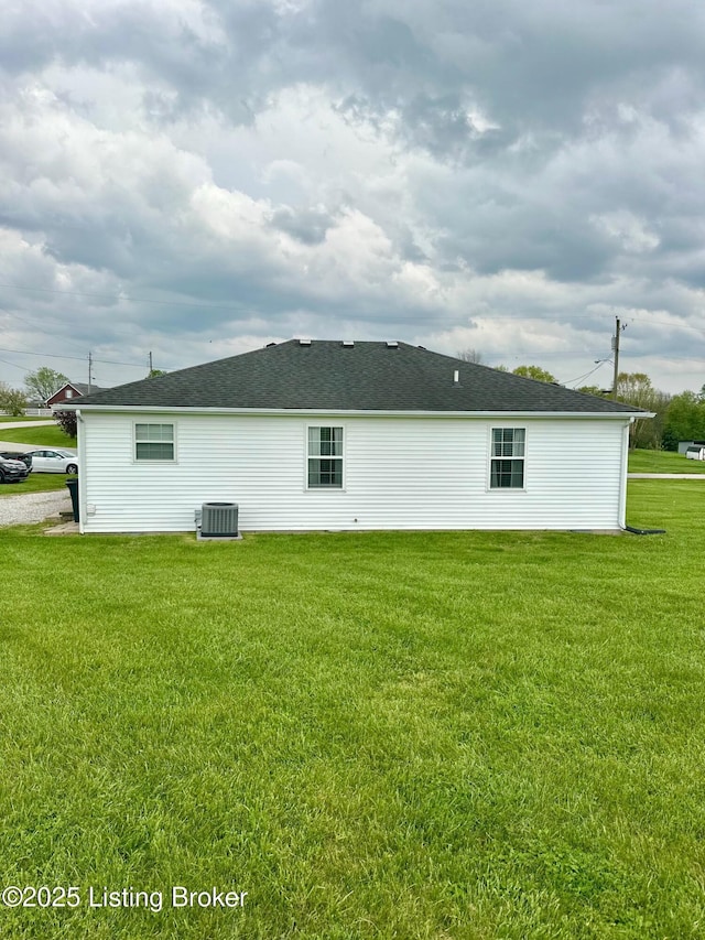 rear view of property featuring a lawn and central AC unit