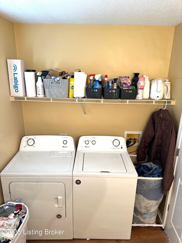 clothes washing area featuring wood finished floors, washer and dryer, and laundry area