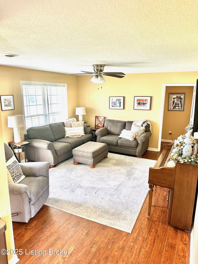 living room with wood finished floors, a textured ceiling, and a ceiling fan
