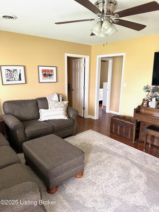 living room with wood finished floors, visible vents, and ceiling fan