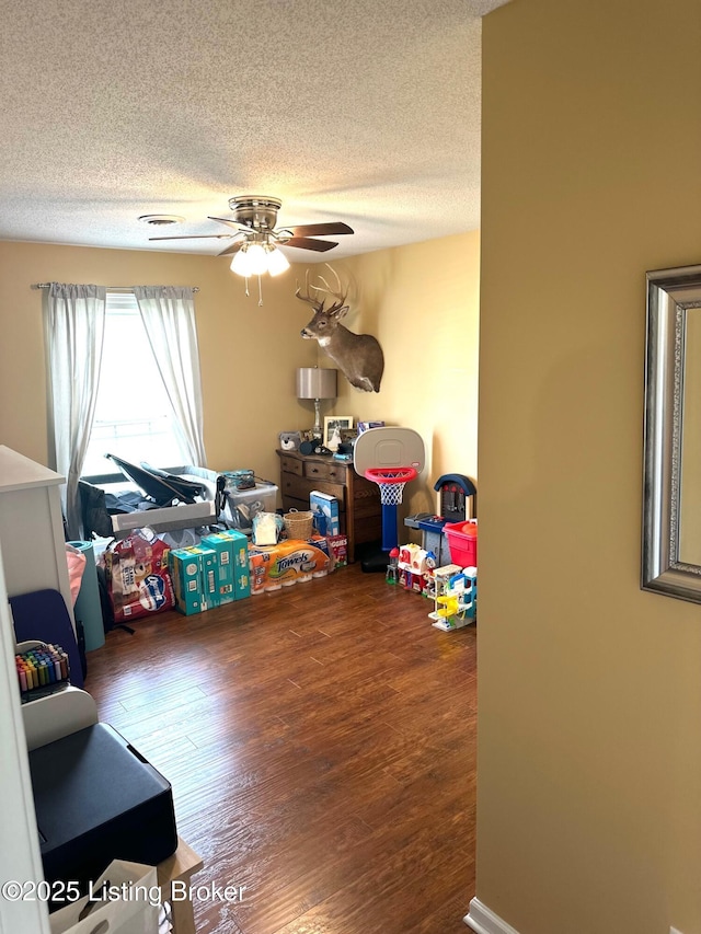 rec room with wood finished floors, a textured ceiling, and ceiling fan