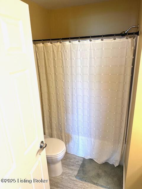 full bath with a shower with curtain, wood finished floors, and toilet