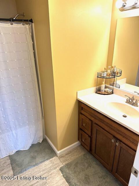 full bath featuring a shower with curtain, baseboards, and vanity