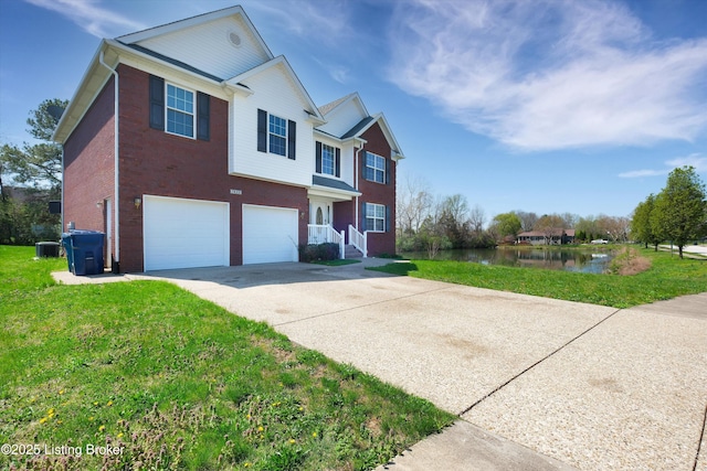 traditional-style house featuring a front lawn, driveway, a water view, a garage, and brick siding