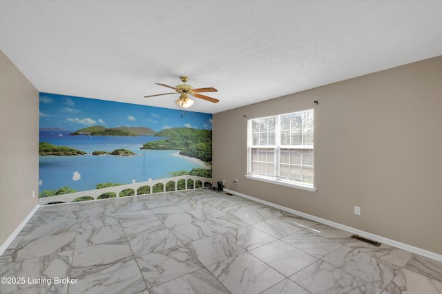 empty room with a ceiling fan, a water view, marble finish floor, baseboards, and visible vents