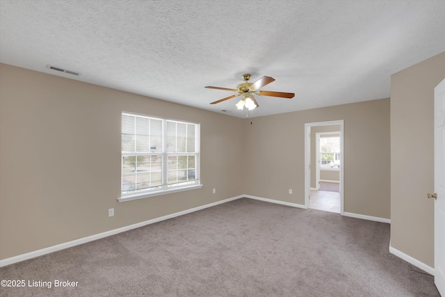 unfurnished room with a ceiling fan, a textured ceiling, carpet, baseboards, and visible vents
