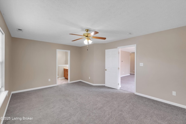 carpeted empty room featuring baseboards, a ceiling fan, visible vents, and a textured ceiling