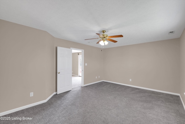 spare room featuring dark carpet, ceiling fan, baseboards, and visible vents
