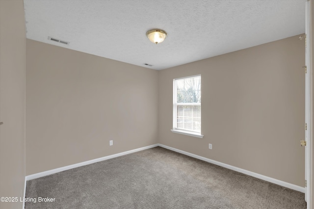 spare room featuring baseboards, carpet flooring, a textured ceiling, and visible vents