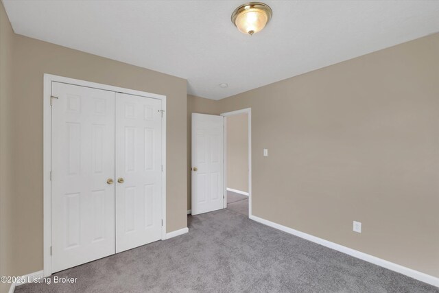 unfurnished bedroom featuring carpet, a closet, and baseboards