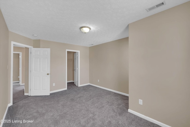 unfurnished bedroom featuring a textured ceiling, carpet, visible vents, and baseboards