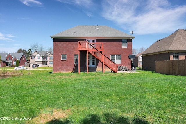 rear view of house with a lawn, brick siding, a deck, and stairs