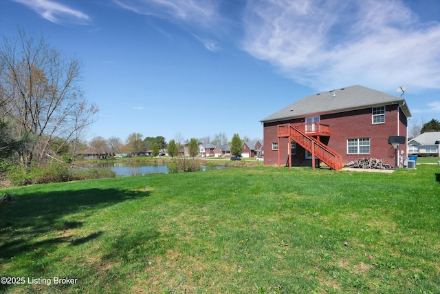 view of yard featuring a deck with water view and stairs