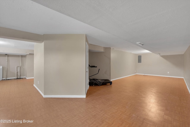finished below grade area featuring electric panel, baseboards, a textured ceiling, and parquet floors