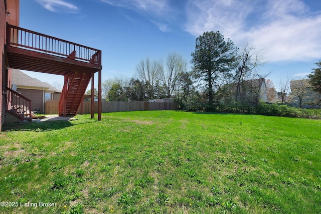 view of yard featuring a wooden deck, fence, and stairs