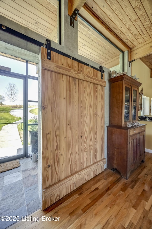 room details with wooden ceiling, beam ceiling, a barn door, and wood finished floors