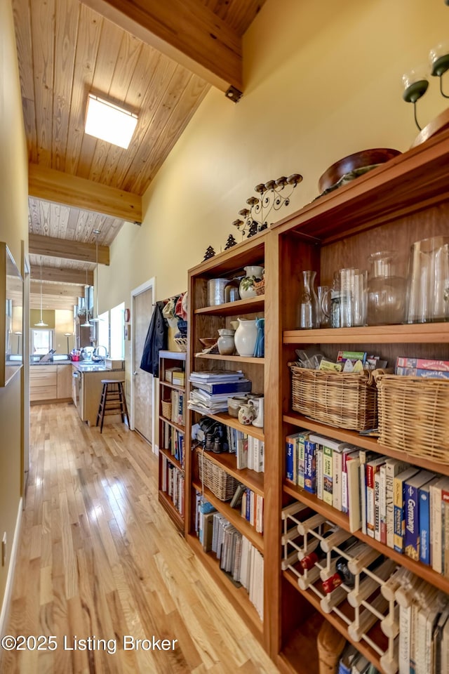 interior space with light wood-style flooring, wooden ceiling, and beam ceiling