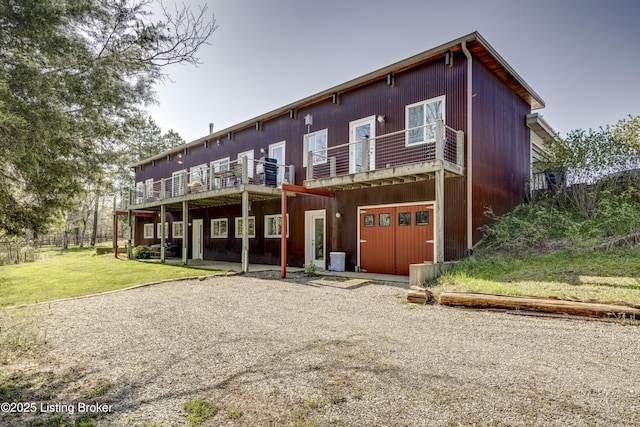 rear view of house featuring a wooden deck, cooling unit, a lawn, and gravel driveway