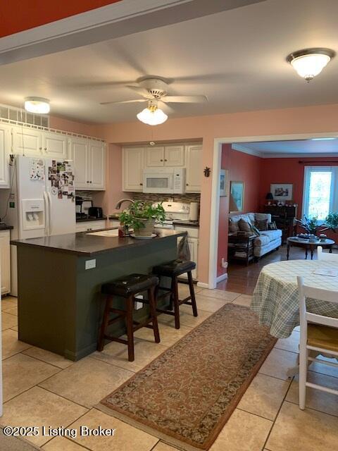 325 Rosewood Dr, Louisville, KY 40223 - kitchen featuring white appliances, dark countertops, white cabinets, light tile patterned floors, and a kitchen island