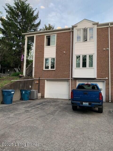 325 Rosewood Dr, Louisville, KY 40223 - back of house with asphalt driveway, brick siding, central AC, and an attached garage